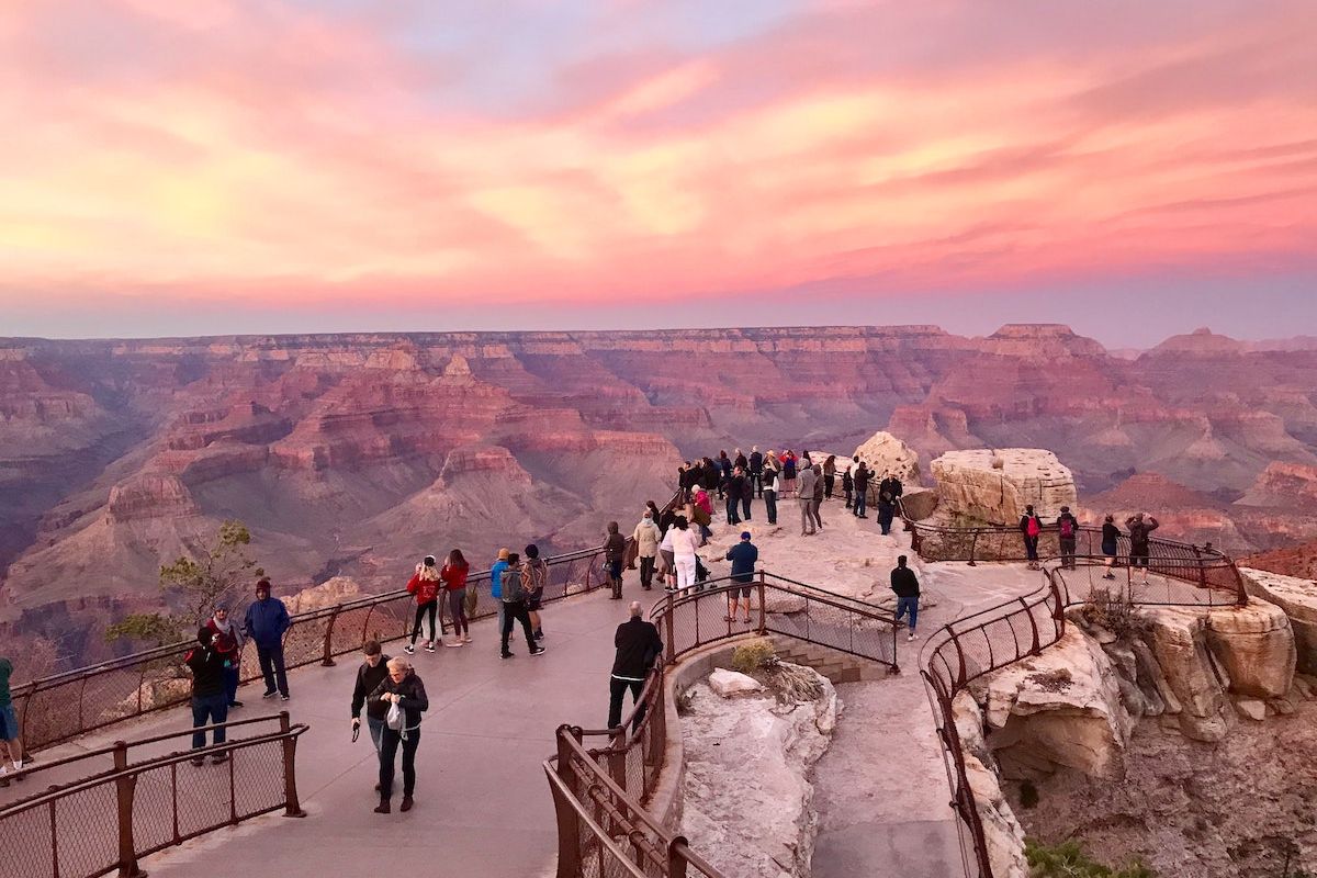 People enjoy a Grand Canyon overlook at sunset, making it a stunning choice for day trips from Phoenix or Scottsdale.