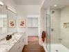 Modern bathroom with double vanity, glass shower, abstract art, and a walk-in closet—showcasing stylish bathroom design throughout.