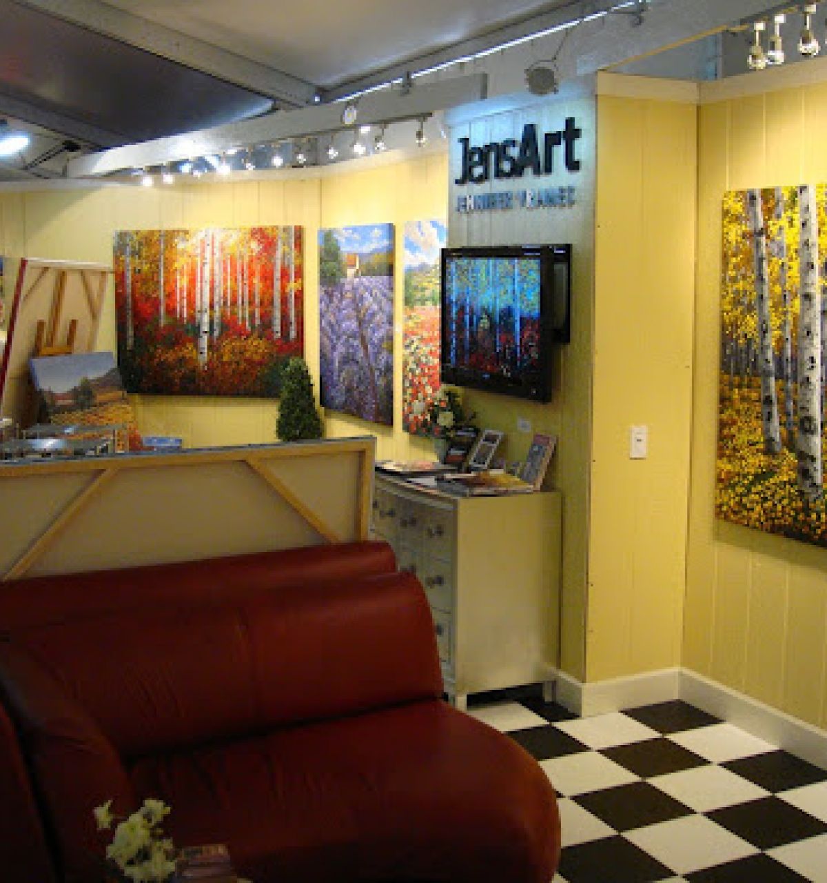 Art gallery with colorful landscape paintings, a red couch, and checkered floor—your art guide to Scottsdale’s Celebration of Fine Art.