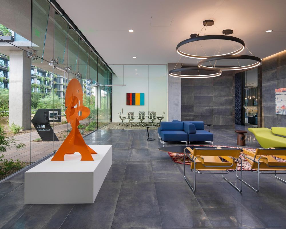 Modern office lobby with colorful abstract art, glass walls, and contemporary furniture.