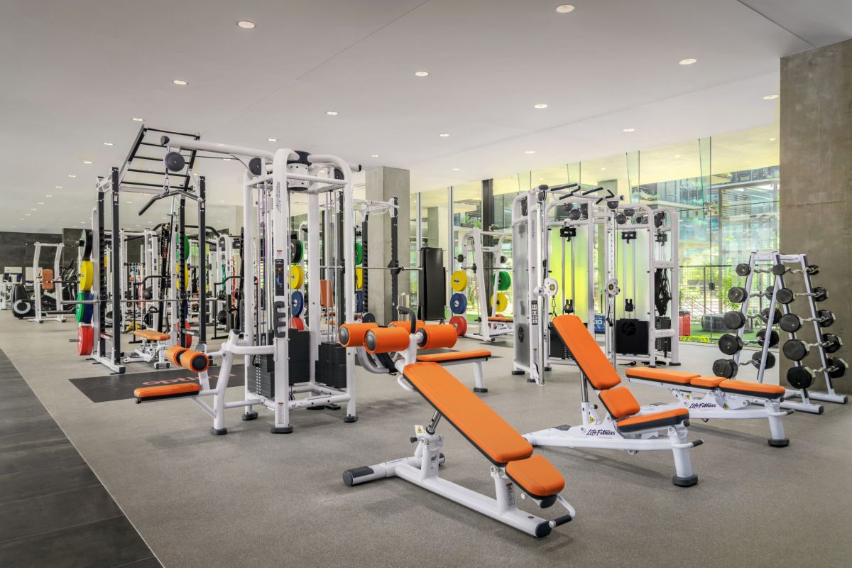 Modern fitness center with orange benches, weight machines, free weights, and large mirrors to support your daily habit.