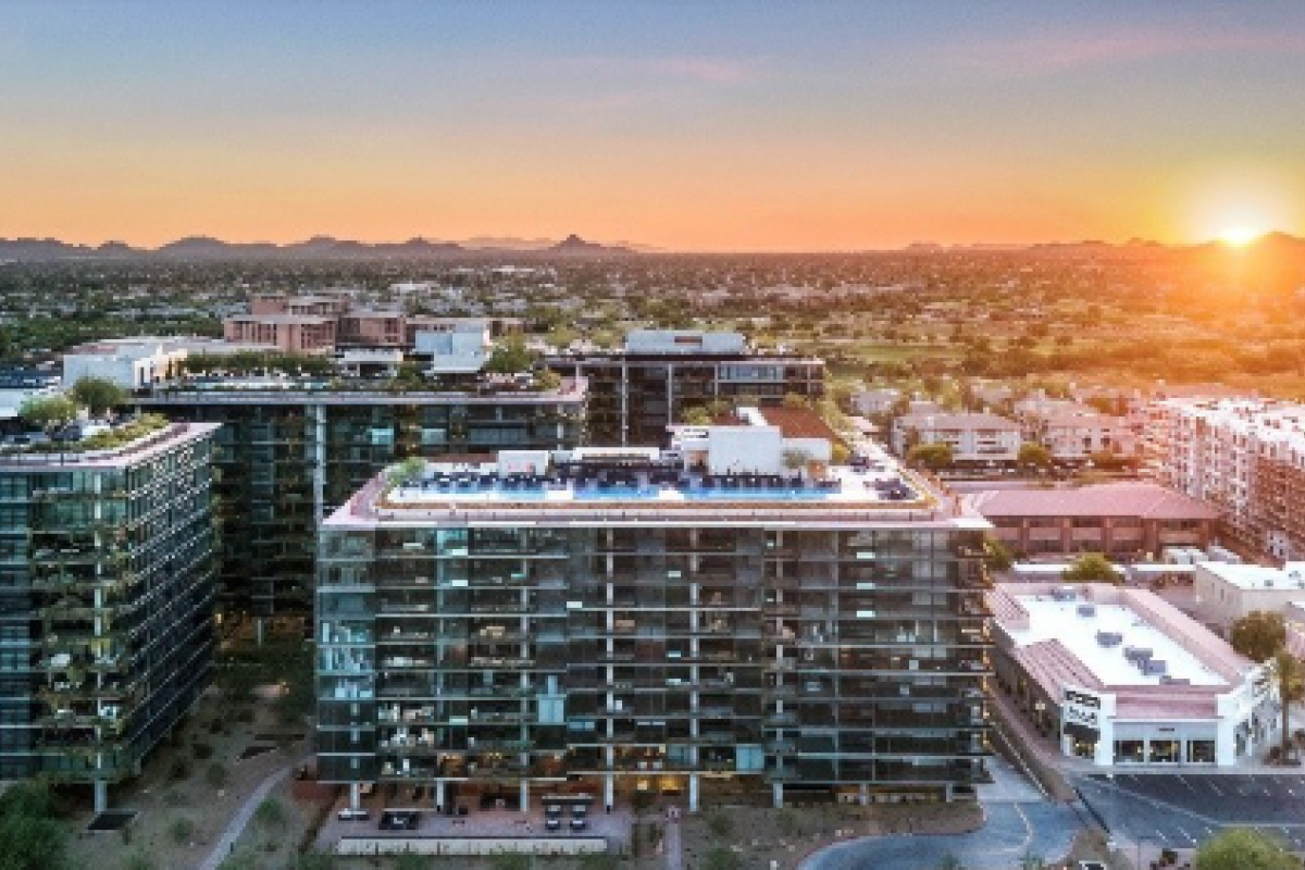Aerial view of modern city buildings at sunset with mountains in the background.