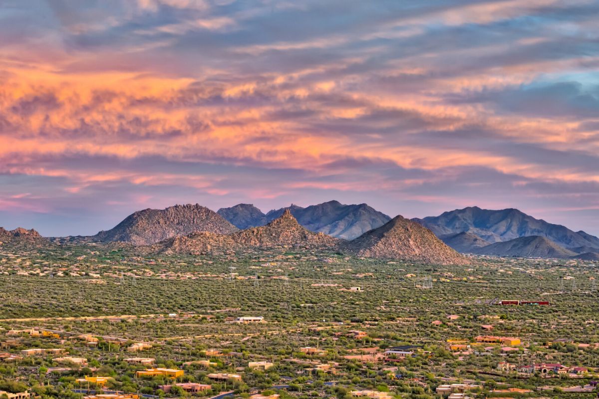 Colorful sunset sky over desert mountains and scattered houses near Scottsdale's McDowell Sonoran Preserve.