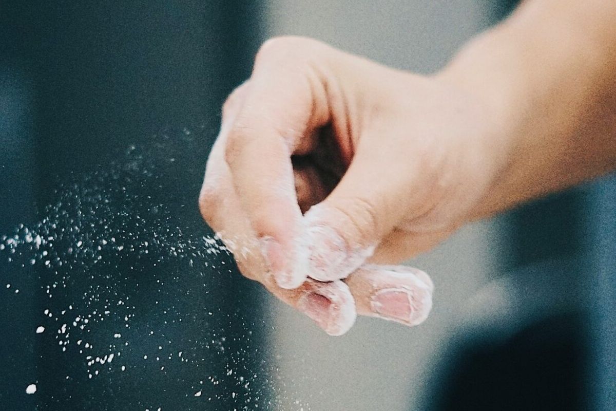 A hand sprinkling white flour, with flour dust in the air—perfect for those embracing sustainable living in the kitchen.