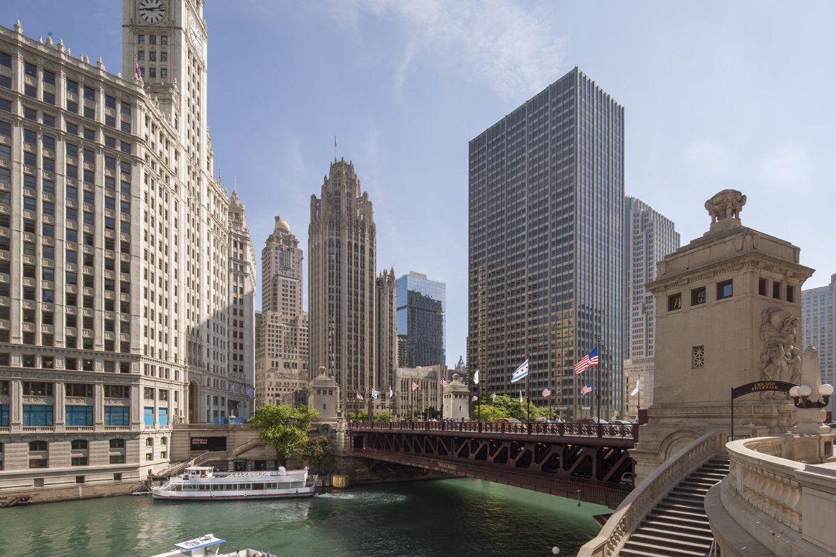 Chicago River with tour boat, Wrigley Building, skyscrapers, and DuSable Bridge—blue space water features boost mental wellness on a sunny day.