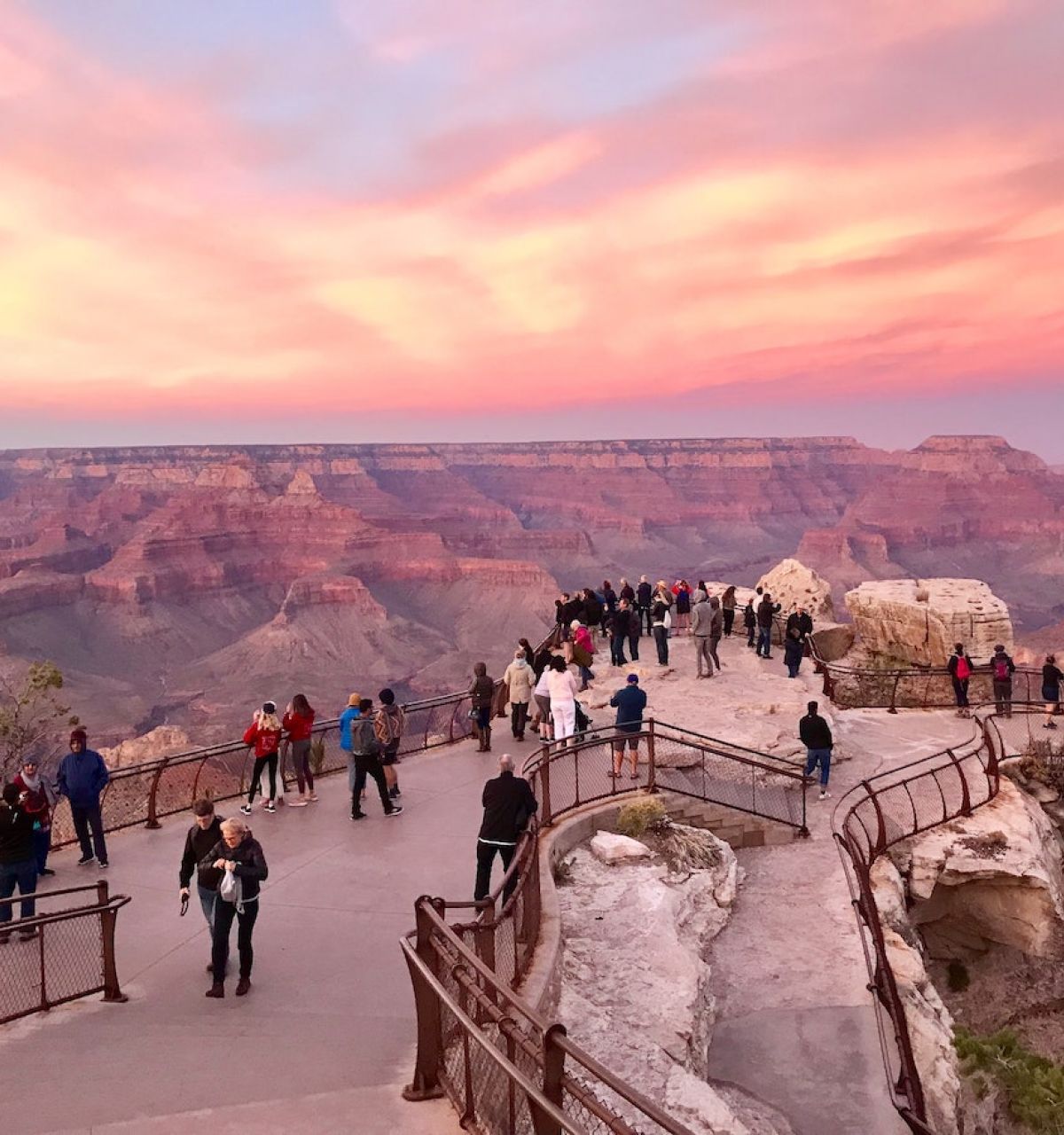 People enjoy a Grand Canyon overlook at sunset, making it a stunning choice for day trips from Phoenix or Scottsdale.