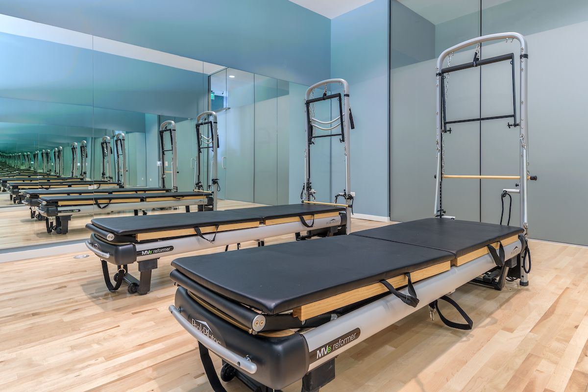 A modern Pilates studio with two reformer machines, mirrored walls, and a light wood floor for a stronger self.