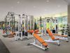 Modern fitness center with orange benches, weight machines, free weights, and large mirrors to support your daily habit.