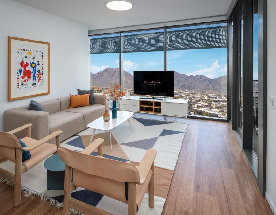 Modern living room with large windows, mountain view, stylish furniture, and colorful wall art.