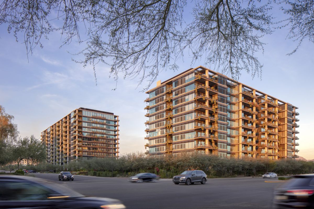 Two modern apartment buildings at sunset offer a short commute and commuting benefits, with cars driving on the street in the foreground.