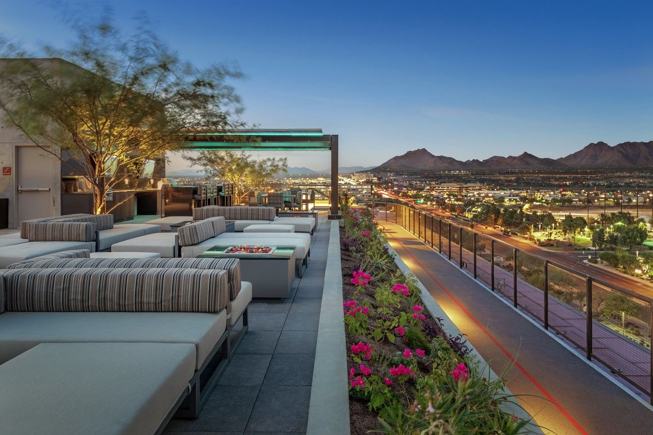 Modern rooftop terrace lounge at Optima Kierland with fire pits, vibrant flowers, and breathtaking views—perfect for walkable urban living.