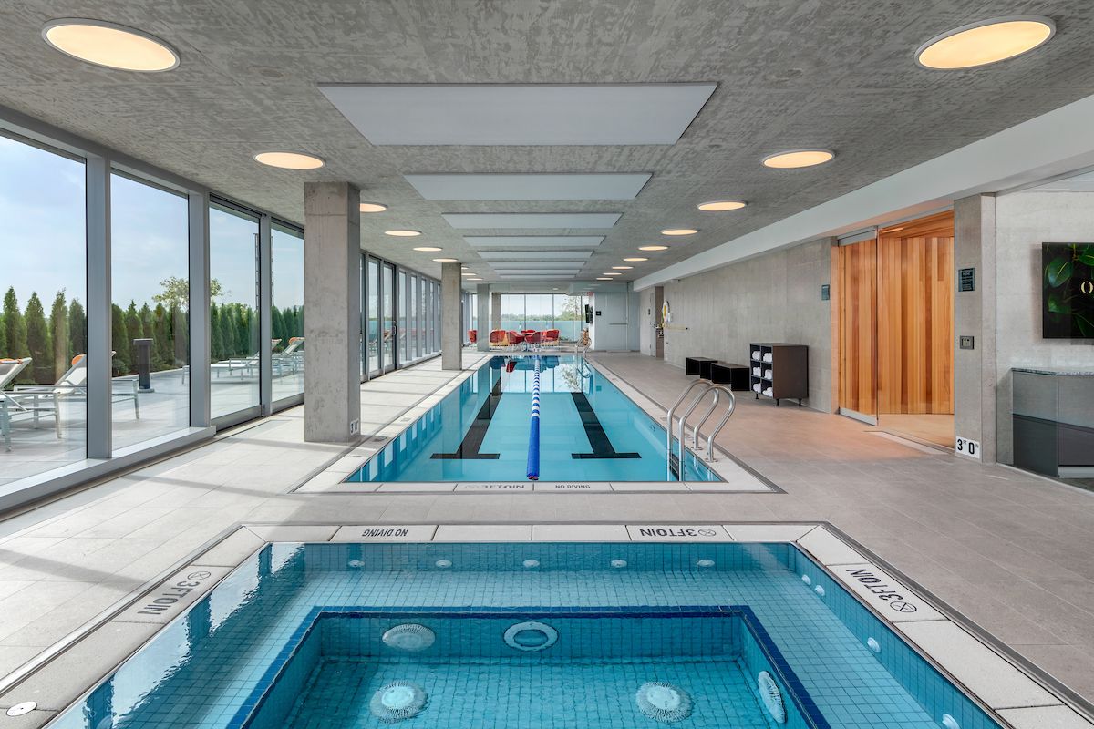 Indoor pool area with a hot tub, perfect for Winter Wellness and relaxation by the large windows at Optima.