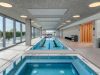 Indoor pool area with a hot tub, perfect for Winter Wellness and relaxation by the large windows at Optima.