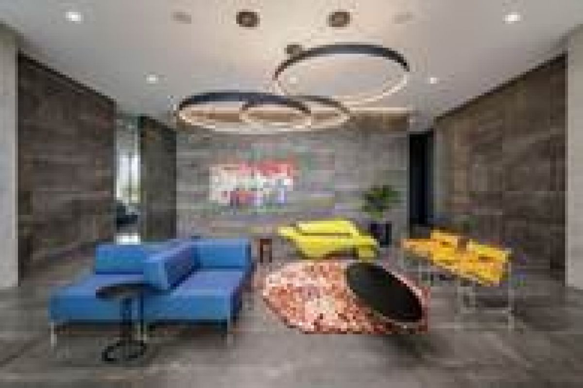 Modern lounge with blue and yellow seating, circular light fixtures, and colorful wall art.
