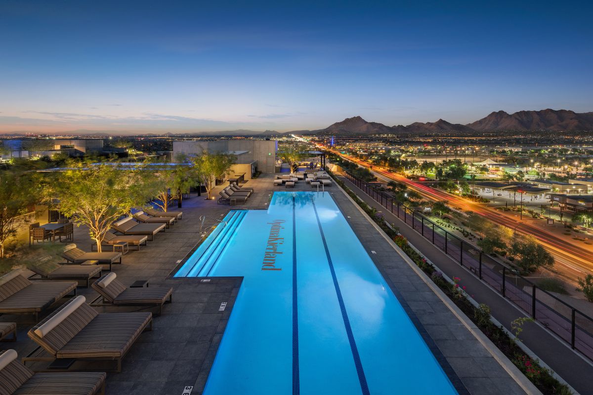 Rooftop infinity pool with lounge chairs at dusk, offering stunning city views and Optima Sky Decks' signature rooftop amenities.