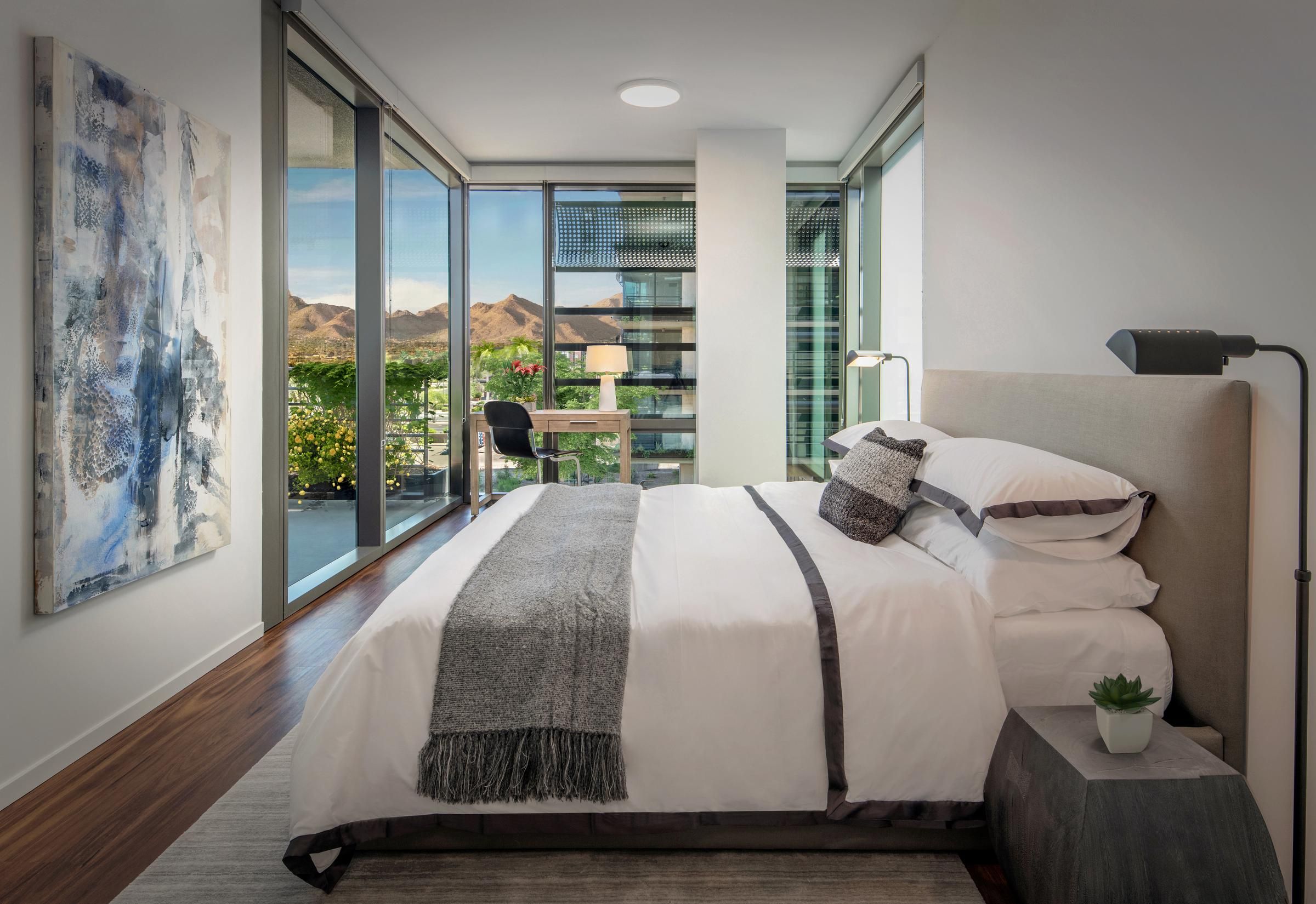 View from Optima Sonoran Village apartment rooftop of suburban neighborhood with desert landscaping and a mountain backdrop at sunset.