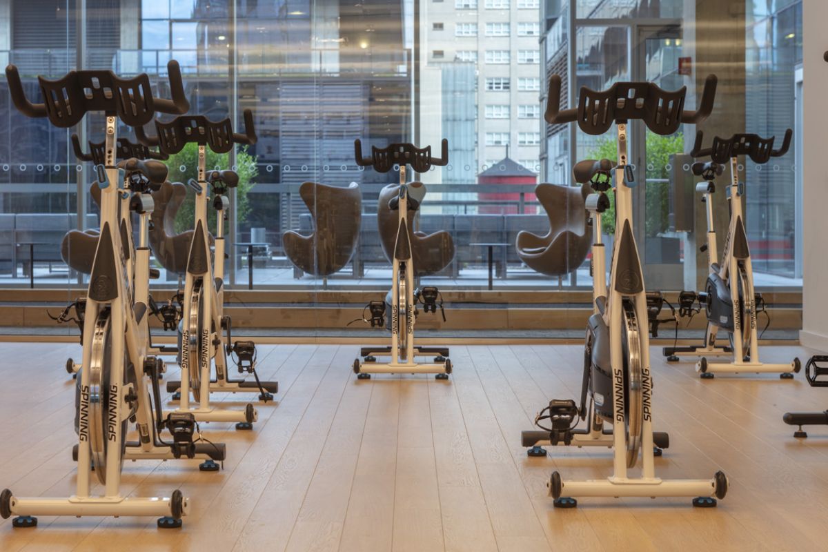 Several stationary bikes are arranged in a modern gym, offering indoor cycling and city views for maximum cycling fitness.