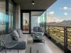 Modern Optima balcony with gray seating, glass railings, and mountain views—an inviting outdoor space under a partly cloudy sky.