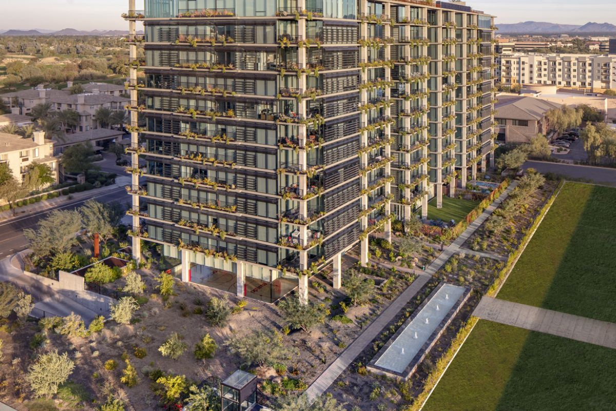 A modern apartment building with glass balconies, featuring vertical landscaping and a rectangular water feature at Optima Kierland.