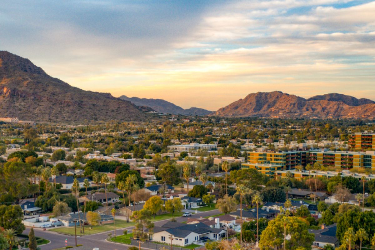 Aerial view of suburban homes with a mountain backdrop—perfect for those seeking renting tips before choosing a residence at sunset.