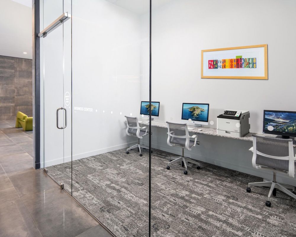 Small business center with three computers, office chairs, a printer, and colorful art on the wall.