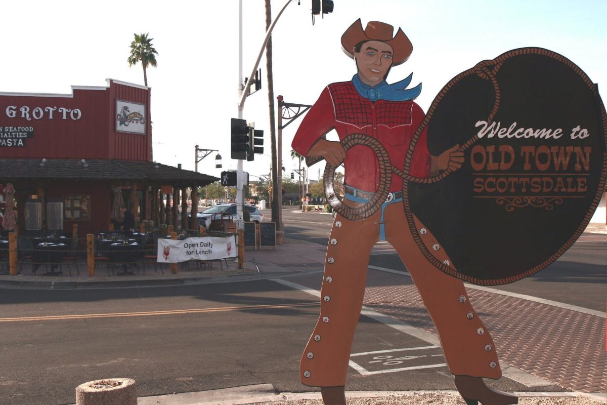 A cowboy sign welcomes visitors to Old Town Scottsdale, highlighting the area’s rich Western heritage on a sunny street corner.