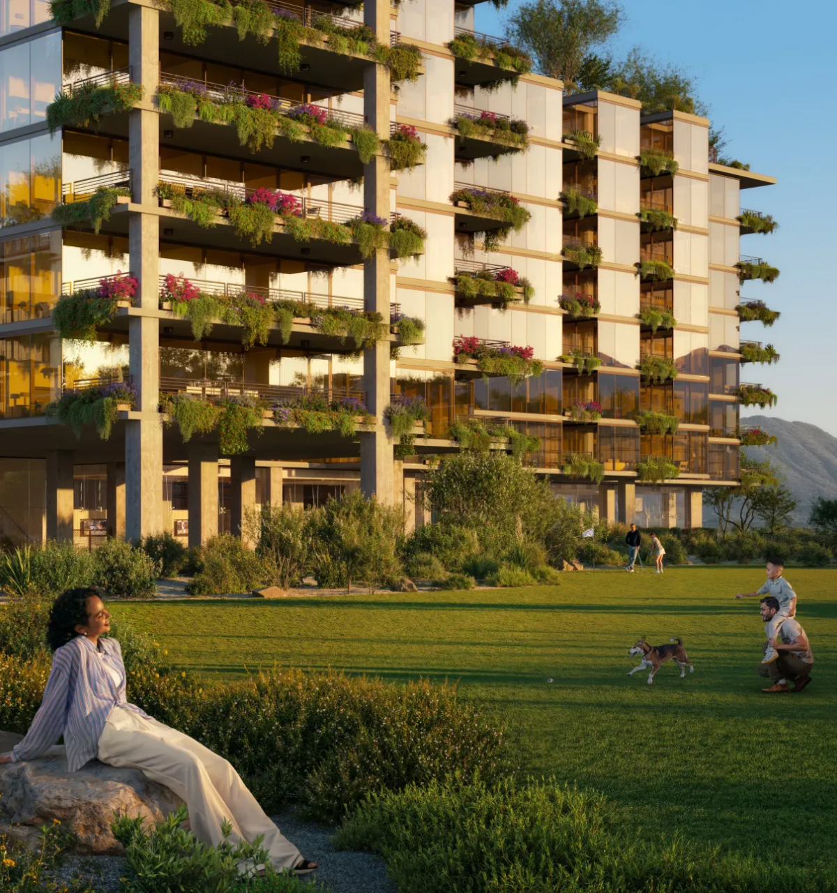 Woman relaxing on grass near modern apartment building, embracing mental clarity as people walk dogs outside.