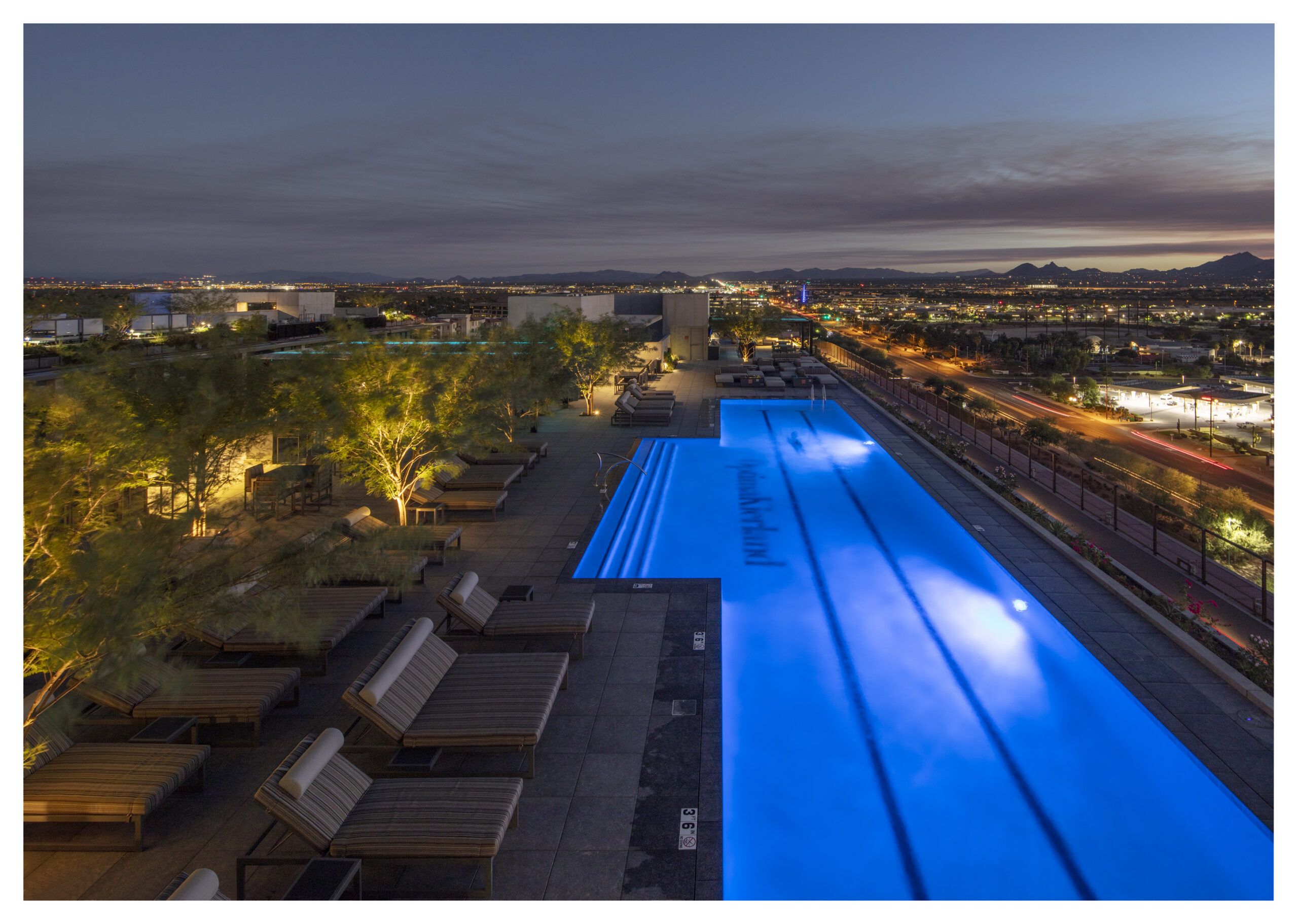 Experience apartment living at its finest with a rooftop pool glowing at night at Optima Kierland Apartments, overlooking the cityscape.