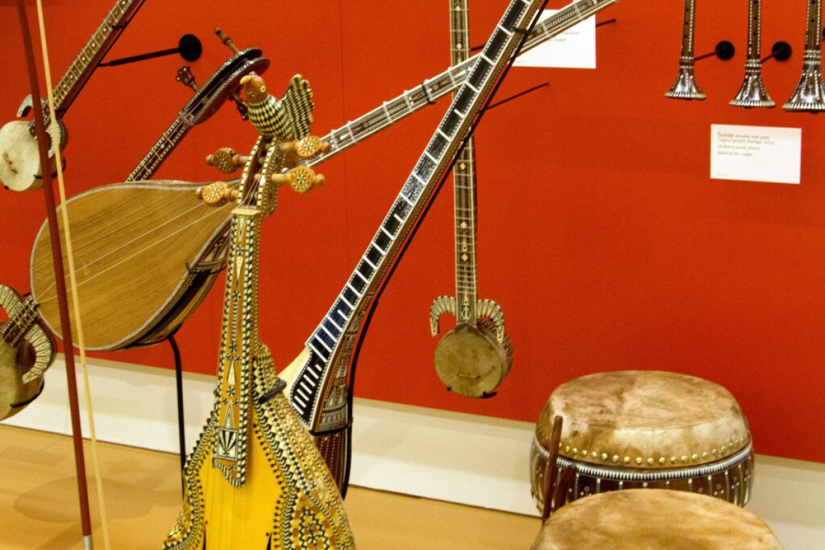 Traditional string and percussion instruments displayed against a red wall at the Musical Instrument Museum in Scottsdale, showcasing rhythms of the world.