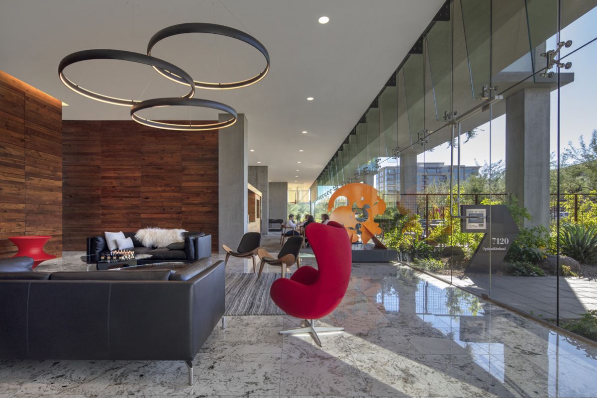 Modern lobby with black leather couches, red accent chair, large windows, and circular ceiling lights showcase bold color palettes.