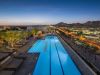 Rooftop infinity pool with lounge chairs at dusk, offering stunning city views and Optima Sky Decks' signature rooftop amenities.