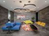 Modern lounge with blue and yellow seating, circular light fixtures, and colorful wall art.