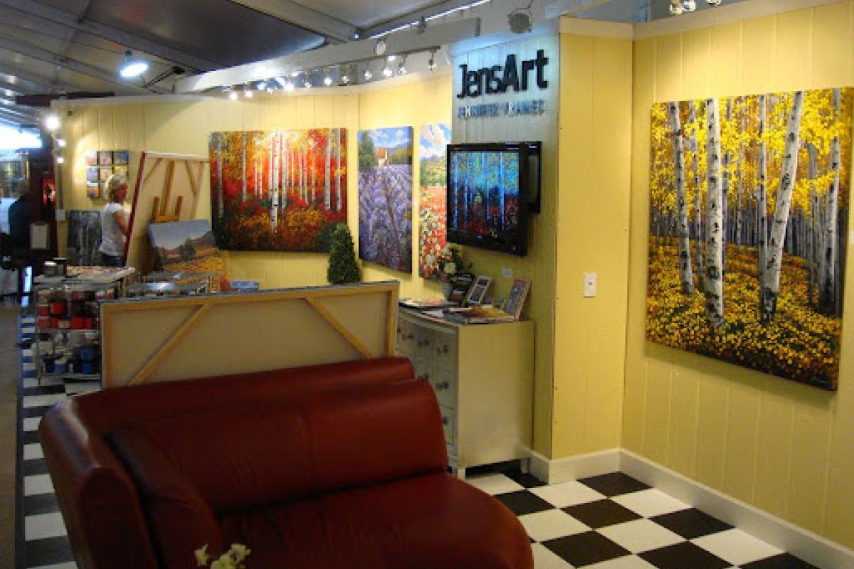 Art gallery with colorful landscape paintings, a red couch, and checkered floor—your art guide to Scottsdale’s Celebration of Fine Art.