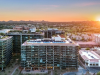 Aerial view of modern city buildings at sunset with mountains in the background.