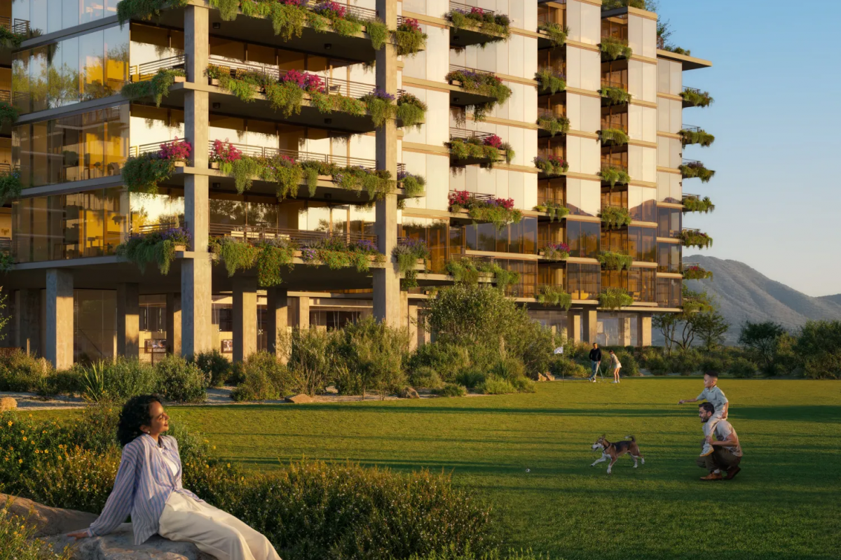Woman relaxing on grass near modern apartment building, embracing mental clarity as people walk dogs outside.