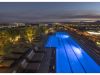 Rooftop pool glowing blue at dusk, with lounge chairs—perfect for Sky Deck evenings amid city lights and distant mountains.