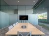 Modern conference room with a long table, chairs, TV screen, glass walls, and an Optima work design for a home office feel.