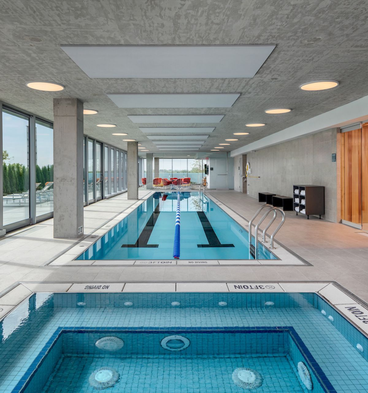 Indoor pool area with a hot tub, perfect for Winter Wellness and relaxation by the large windows at Optima.