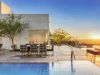 Modern rooftop pool and lounge at sunset, featuring seating, trees, and mountain views—designed with sustainable development in mind.