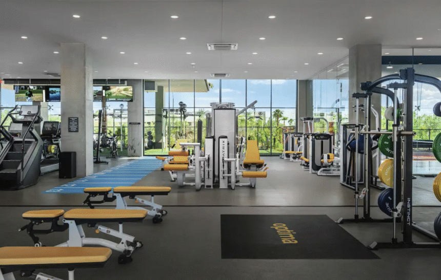 Modern gym with Optima yellow and white fitness equipment, large windows, and a view of greenery perfect for winter wellness.