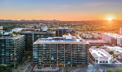 Aerial view of modern city buildings at sunset with mountains in the background.