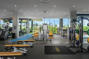 Modern gym with yellow benches, weight machines, and large windows letting in natural light.