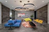 Modern lounge with blue and yellow seating, circular light fixtures, and colorful wall art.