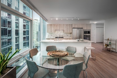 Modern kitchen and dining area with glass table, gray chairs, large windows, and city views.