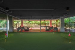 Indoor mini-golf putting green with three holes, red flags, and seating area in the background.