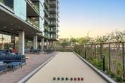 Experience effortless wellness with an outdoor bocce ball court beside a modern apartment and inviting seating area.